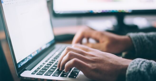 Two hands typing on a laptop