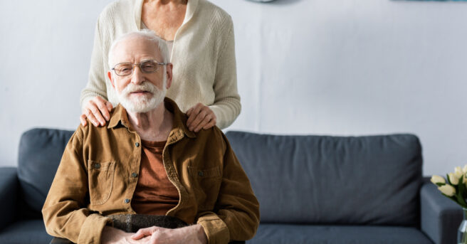 Older person sits in a wheelchair with a loved one behind them
