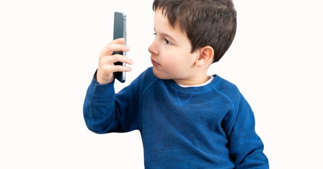 Boy holding a phone up close to his face, trying to read the screen.